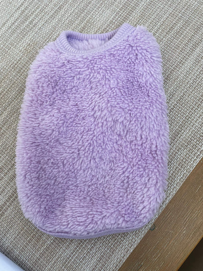 Small dog fluffy vest in light purple on a textured surface.